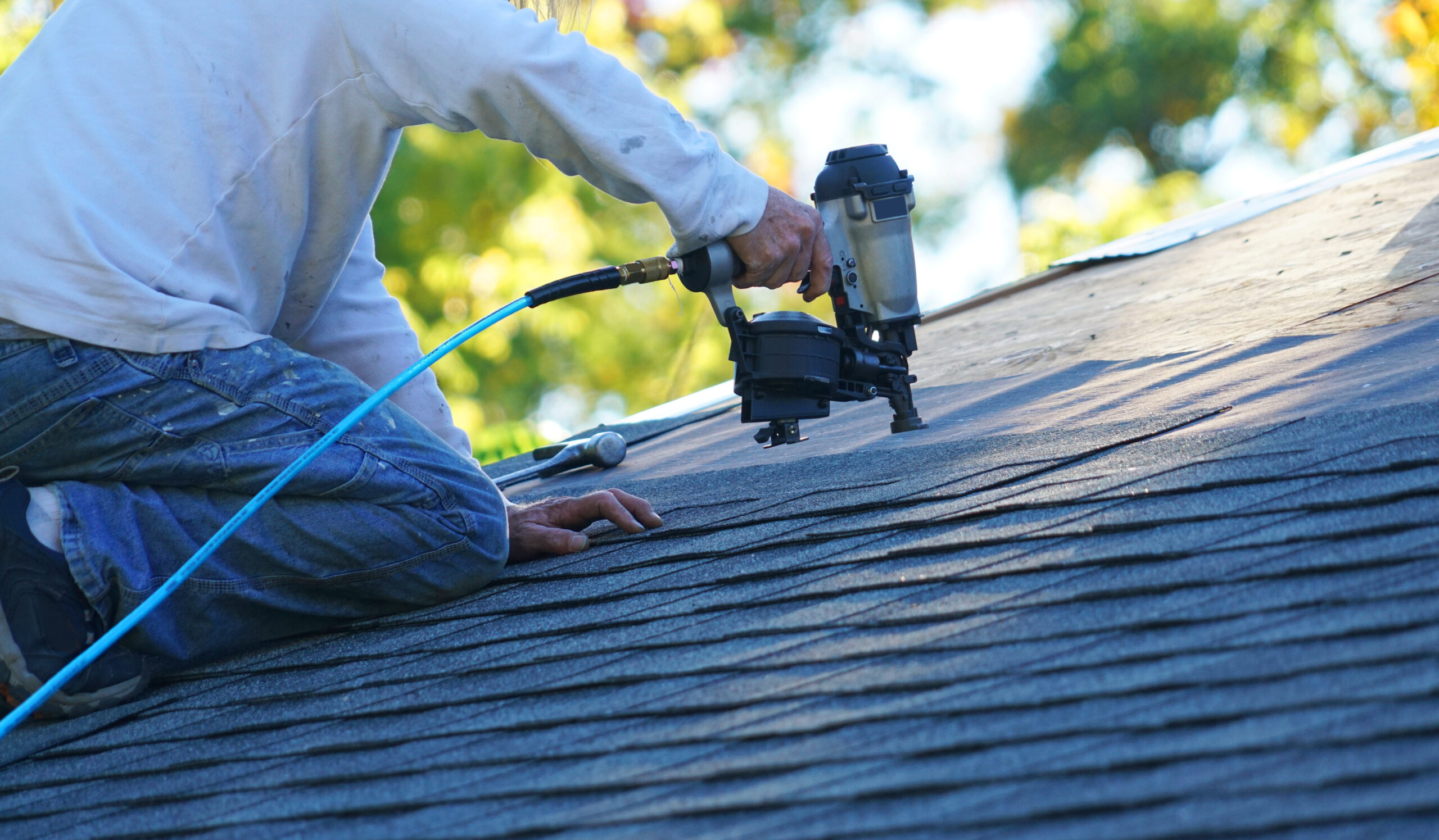 handyman using nail gun to install shingle to repair roof shingle installation